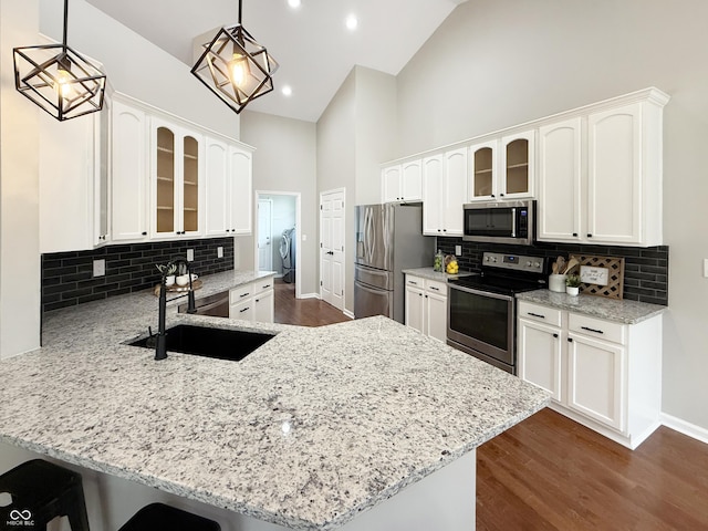 9302 N Bayland Dr, Mccordsville, IN 46055 - kitchen with appliances with stainless steel finishes, washing machine and dryer, a peninsula, glass insert cabinets, and high vaulted ceiling