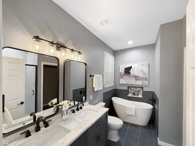 9302 N Bayland Dr, Mccordsville, IN 46055 - bathroom featuring tile walls, double vanity, a freestanding tub, a shower stall, and a wainscoted wall