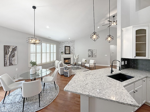 9302 N Bayland Dr, Mccordsville, IN 46055 - kitchen with a large fireplace, white cabinets, dark wood finished floors, a ceiling fan, and backsplash