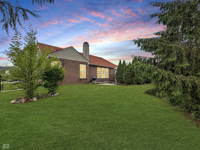 9302 N Bayland Dr, Mccordsville, IN 46055 - back of property at dusk with a chimney, a yard, and brick siding