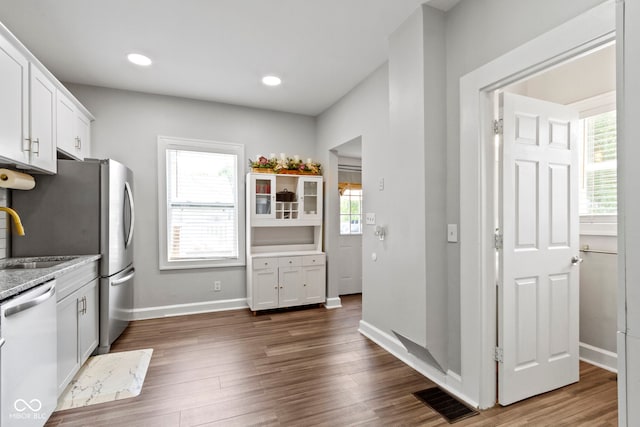 3045 Ruckle St, Indianapolis, IN 46205 - kitchen with dishwasher, dark wood-style flooring, white cabinets, light stone countertops, and freestanding refrigerator