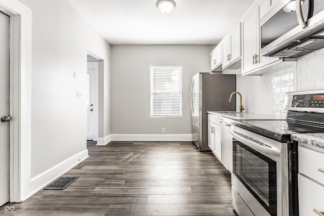 3045 Ruckle St, Indianapolis, IN 46205 - kitchen with stainless steel appliances, decorative backsplash, white cabinetry, light stone counters, and dark wood-style flooring