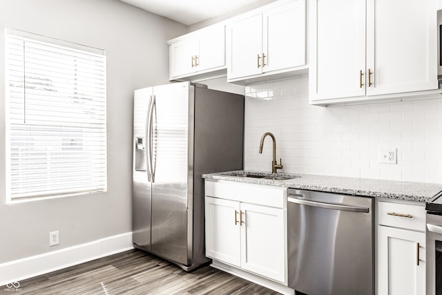 3045 Ruckle St, Indianapolis, IN 46205 - kitchen featuring appliances with stainless steel finishes, wood finished floors, tasteful backsplash, white cabinetry, and light stone counters
