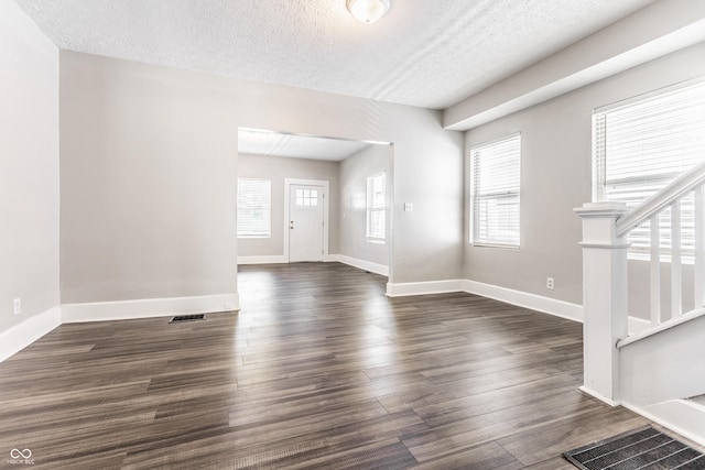 3045 Ruckle St, Indianapolis, IN 46205 - unfurnished living room with stairs, plenty of natural light, a textured ceiling, and dark wood-style floors