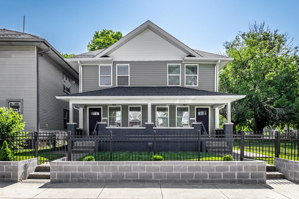 3045 Ruckle St, Indianapolis, IN 46205 - american foursquare style home with covered porch, a shingled roof, and a fenced front yard