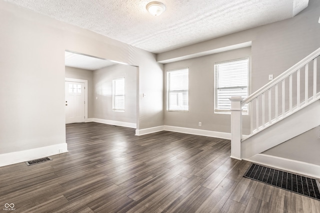 3045 Ruckle St, Indianapolis, IN 46205 - unfurnished living room featuring stairs, dark wood-style floors, plenty of natural light, and a textured ceiling