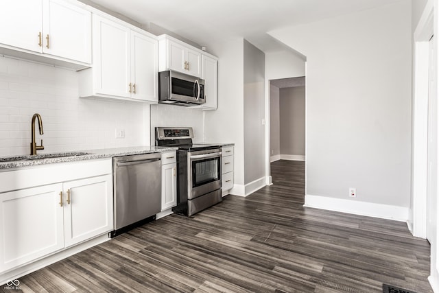3045 Ruckle St, Indianapolis, IN 46205 - kitchen with appliances with stainless steel finishes, decorative backsplash, light stone countertops, white cabinetry, and dark wood-style floors