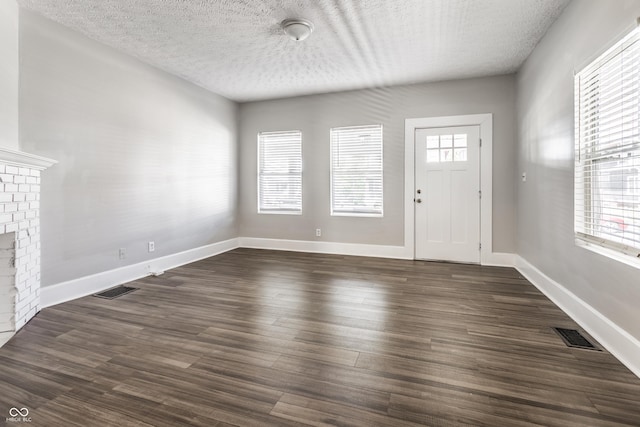 3045 Ruckle St, Indianapolis, IN 46205 - entrance foyer with a fireplace, a textured ceiling, and dark wood-style flooring