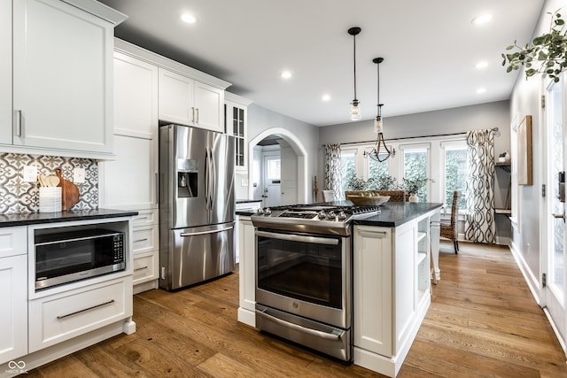 5760 Central Ave N, Indianapolis, IN 46220 - kitchen with appliances with stainless steel finishes, dark countertops, wood finished floors, white cabinetry, and arched walkways