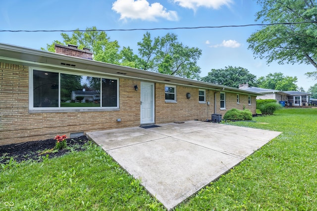 5205 Staughton Dr, Indianapolis, IN 46226 - rear view of property with a patio area, a yard, brick siding, and a chimney