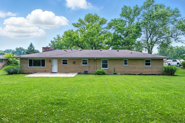 5205 Staughton Dr, Indianapolis, IN 46226 - back of property featuring a patio, a lawn, a chimney, and brick siding