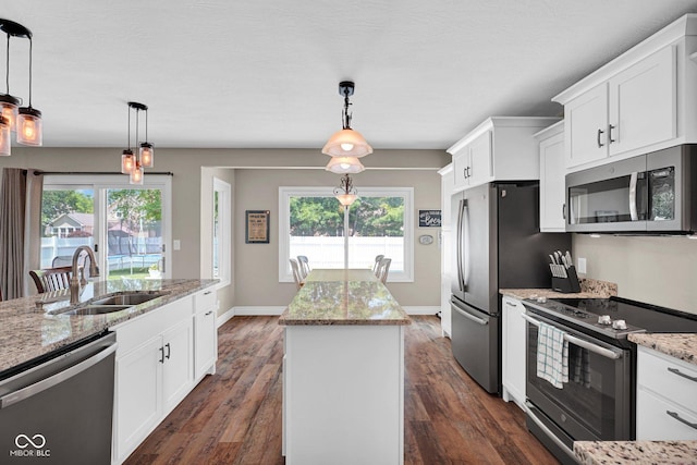2384 Fairfax Dr, Columbus, IN 47203 - kitchen featuring appliances with stainless steel finishes, a kitchen island, white cabinets, light stone counters, and healthy amount of natural light