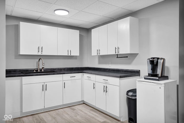2384 Fairfax Dr, Columbus, IN 47203 - kitchen with white cabinets, light wood finished floors, a drop ceiling, and dark countertops