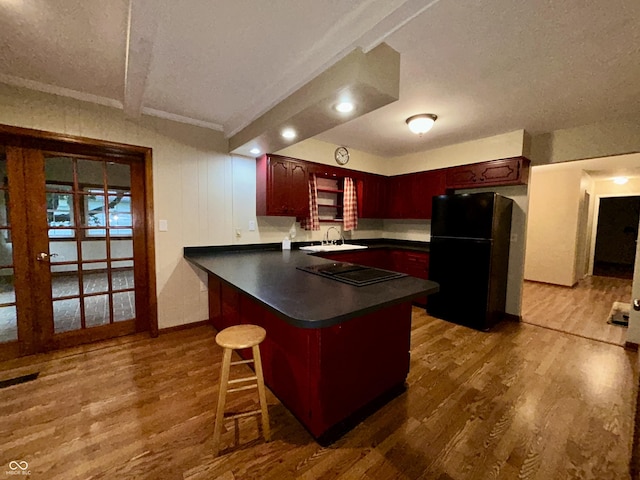 7721 Hollybrook Ln, Indianapolis, IN 46227 - kitchen with black appliances, dark countertops, wood finished floors, dark brown cabinets, and a peninsula