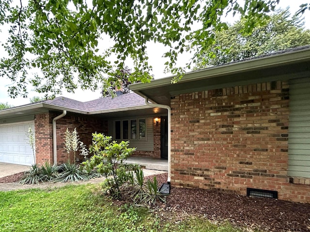 7721 Hollybrook Ln, Indianapolis, IN 46227 - view of side of property featuring an attached garage, brick siding, crawl space, and concrete driveway