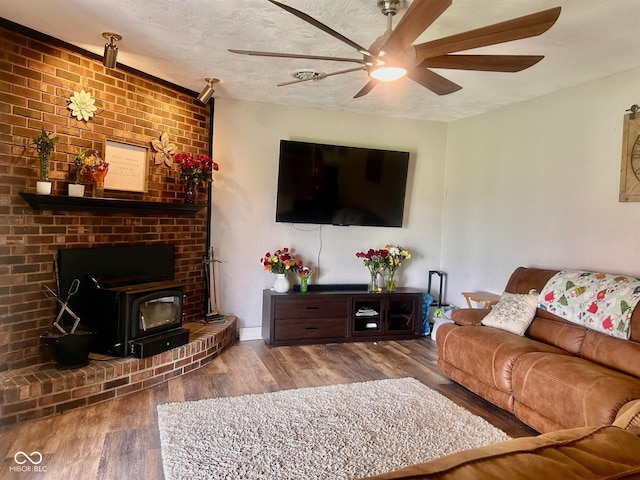 2213 Holden Dr, Anderson, IN 46012 - living room featuring a wood stove, a ceiling fan, wood finished floors, and a textured ceiling
