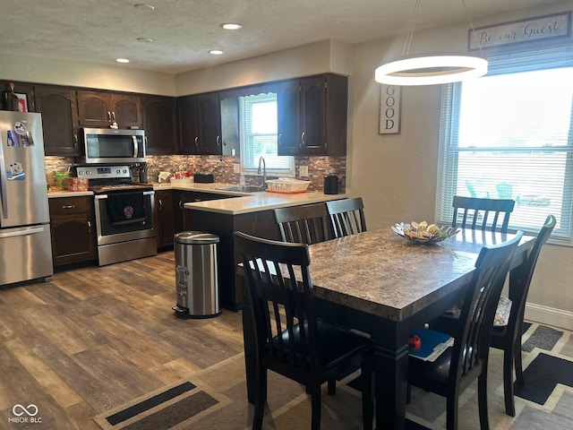 2213 Holden Dr, Anderson, IN 46012 - kitchen featuring appliances with stainless steel finishes, decorative backsplash, dark brown cabinetry, a peninsula, and recessed lighting