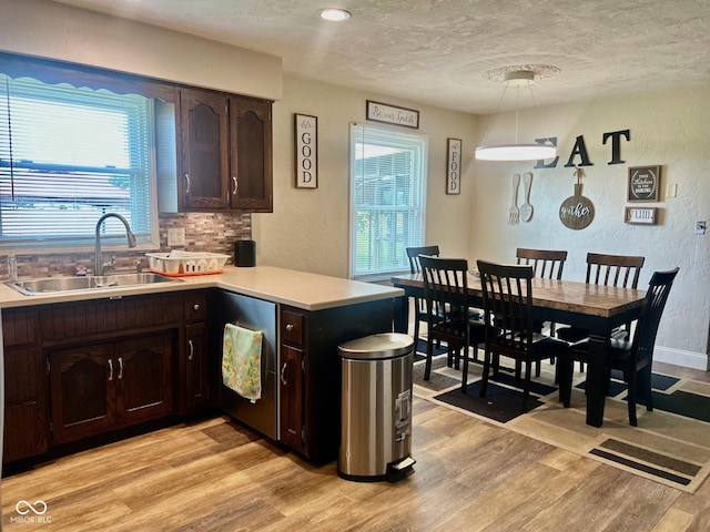 2213 Holden Dr, Anderson, IN 46012 - kitchen featuring a textured wall, light wood-style flooring, dark brown cabinets, a textured ceiling, and a peninsula