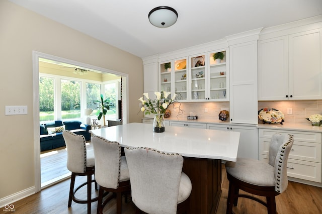 7413 Misty Woods Ln, Indianapolis, IN 46237 - kitchen with white cabinetry, decorative backsplash, a breakfast bar, a kitchen island, and glass insert cabinets