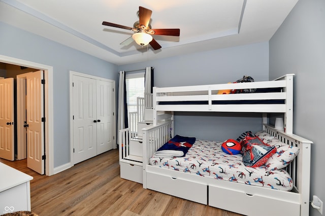 7413 Misty Woods Ln, Indianapolis, IN 46237 - bedroom with light wood-style flooring, a raised ceiling, a closet, and ceiling fan