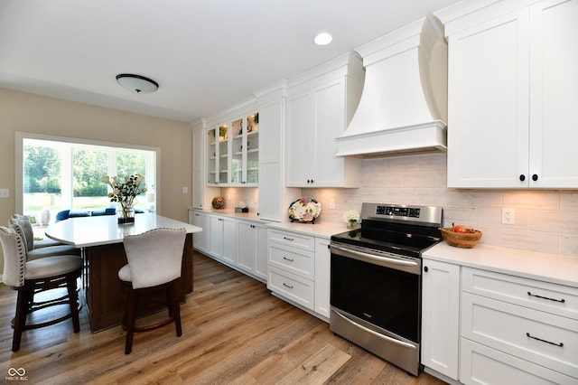 7413 Misty Woods Ln, Indianapolis, IN 46237 - kitchen with stainless steel range with electric stovetop, custom exhaust hood, a kitchen bar, white cabinetry, and recessed lighting