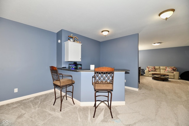 7413 Misty Woods Ln, Indianapolis, IN 46237 - kitchen with light carpet, a breakfast bar area, white cabinetry, and a peninsula