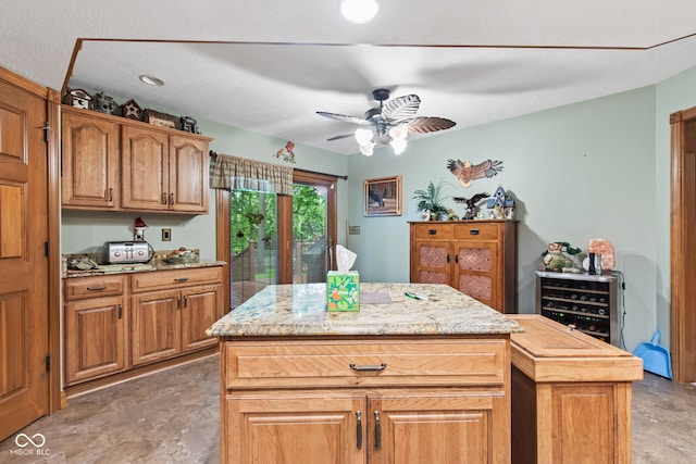 6980 White Oak Dr, Avon, IN 46123 - kitchen featuring ceiling fan, a center island, light stone counters, and brown cabinets