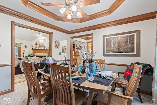 6980 White Oak Dr, Avon, IN 46123 - dining space featuring light carpet, crown molding, ceiling fan, a premium fireplace, and a tray ceiling
