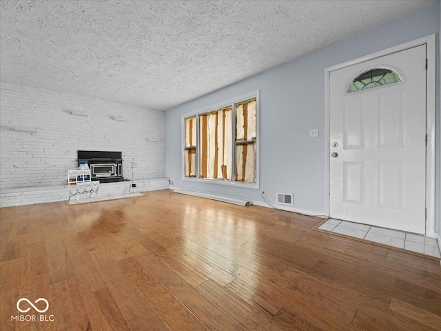 7422 E 33rd St, Indianapolis, IN 46226 - unfurnished living room featuring wood-type flooring, a textured ceiling, and a wood stove