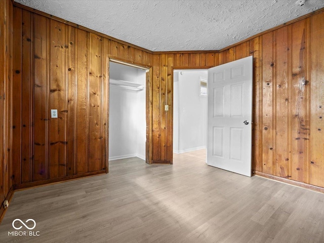 7422 E 33rd St, Indianapolis, IN 46226 - unfurnished bedroom featuring wood finished floors, wooden walls, a closet, a textured ceiling, and crown molding