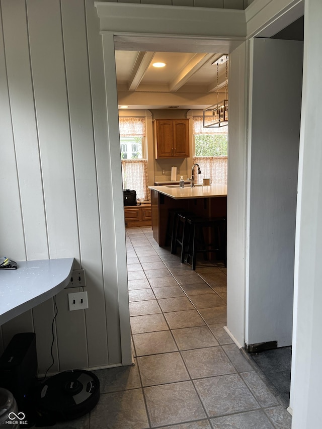 1131 N Main St, Rushville, IN 46173 - kitchen with beam ceiling, a kitchen breakfast bar, light countertops, plenty of natural light, and brown cabinetry