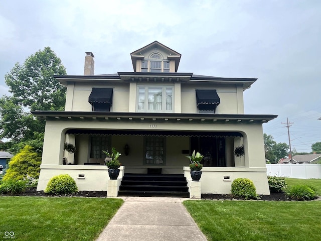 1131 N Main St, Rushville, IN 46173 - american foursquare style home featuring a porch, a front yard, stucco siding, and a chimney