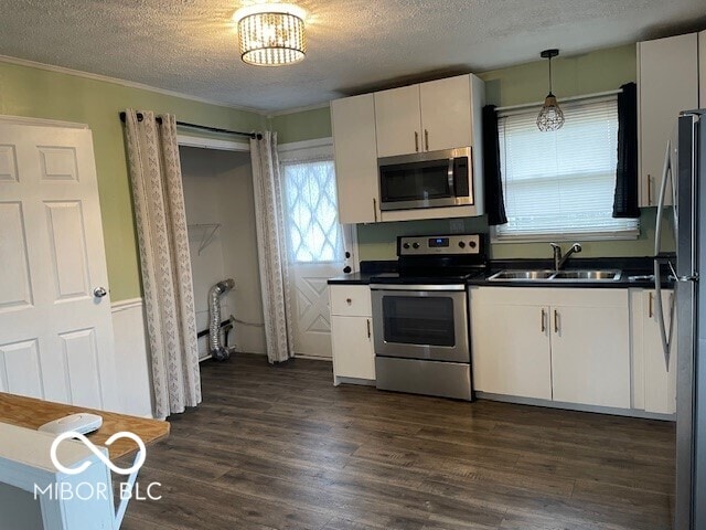 kitchen with appliances with stainless steel finishes, dark countertops, white cabinetry, a textured ceiling, and dark wood-type flooring