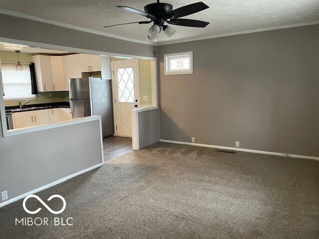 kitchen with freestanding refrigerator, ornamental molding, carpet flooring, a ceiling fan, and white cabinetry