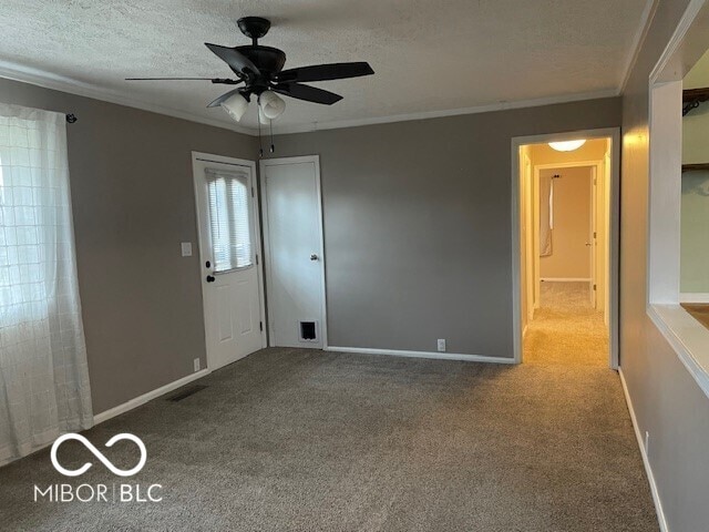 carpeted empty room featuring ornamental molding, a ceiling fan, and a textured ceiling