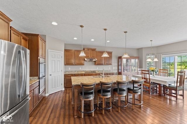 4434 Hickory Ridge Blvd, Greenwood, IN 46143 - kitchen with appliances with stainless steel finishes, dark wood-type flooring, brown cabinetry, under cabinet range hood, and recessed lighting