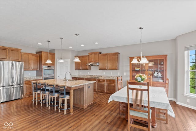 4434 Hickory Ridge Blvd, Greenwood, IN 46143 - kitchen featuring stainless steel appliances, dark wood finished floors, recessed lighting, brown cabinetry, and an island with sink