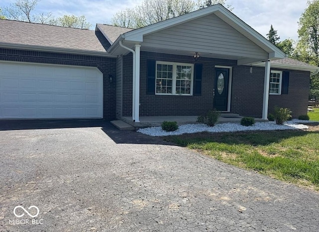 935 S County Road 185 E, North Vernon, IN 47265 - ranch-style house with asphalt driveway, brick siding, a garage, and a porch