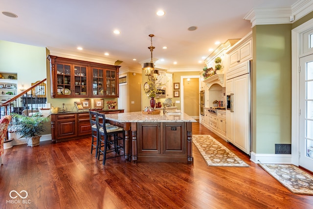 4636 S Hawks Way, Bloomington, IN 47401 - kitchen with appliances with stainless steel finishes, an island with sink, glass insert cabinets, dark wood-type flooring, and ornamental molding