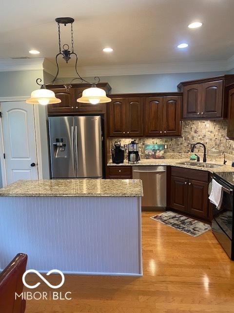 3354 Nottinghill Dr, Plainfield, IN 46168 - kitchen featuring appliances with stainless steel finishes, ornamental molding, dark brown cabinetry, backsplash, and light stone countertops