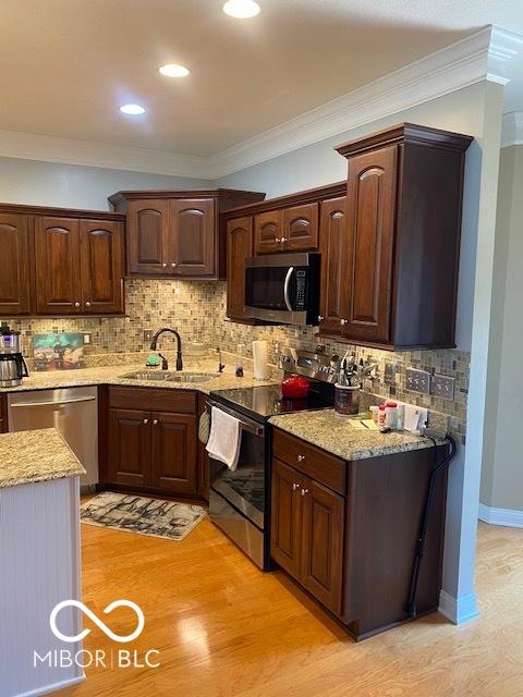 3354 Nottinghill Dr, Plainfield, IN 46168 - kitchen with stainless steel appliances, light stone counters, tasteful backsplash, light wood-style floors, and crown molding