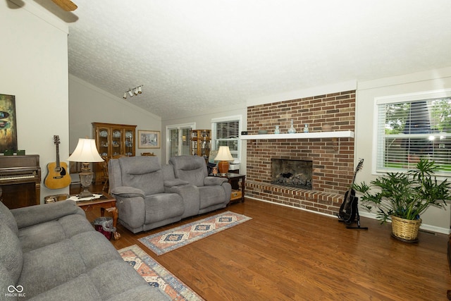 13 Fairlane Dr, Brownsburg, IN 46112 - living area featuring wood finished floors, a textured ceiling, vaulted ceiling, a brick fireplace, and ceiling fan