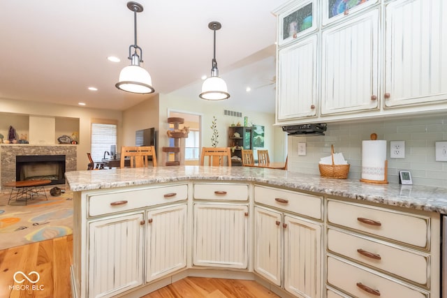 2608 S Trotters Run, Bloomington, IN 47401 - kitchen featuring a peninsula, light wood finished floors, backsplash, vaulted ceiling, and a fireplace