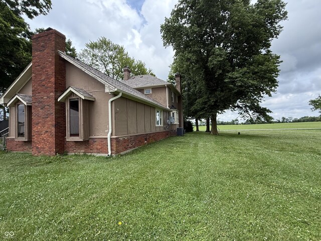 2607 N Henderson Rd, Rushville, IN 46173 - view of side of property with a chimney, brick siding, a yard, and stucco siding