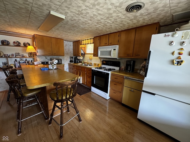 8664 S Nash Dr, Nineveh, IN 46164 - kitchen with white appliances, brown cabinets, dark wood-type flooring, a kitchen breakfast bar, and a peninsula