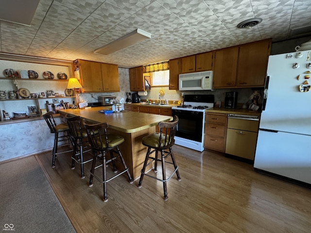 8664 S Nash Dr, Nineveh, IN 46164 - kitchen with white appliances, wood finished floors, brown cabinets, and a breakfast bar area