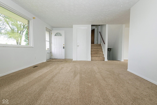 1217 S Post Rd, Indianapolis, IN 46239 - unfurnished living room featuring a textured ceiling, stairway, and carpet floors