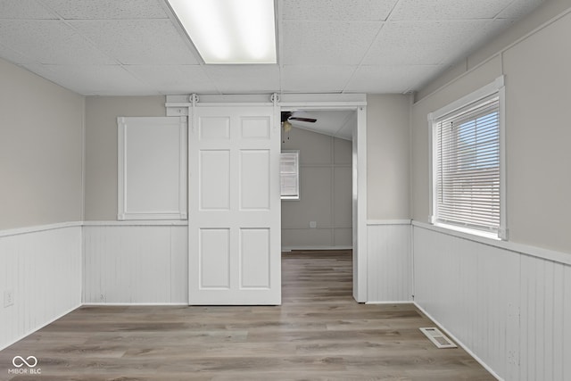 1310 California St, Columbus, IN 47201 - unfurnished bedroom featuring a wainscoted wall, wood finished floors, a drop ceiling, and a decorative wall