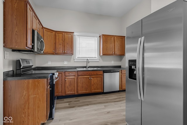 1310 California St, Columbus, IN 47201 - kitchen featuring stainless steel appliances, dark countertops, brown cabinets, and light wood-style floors