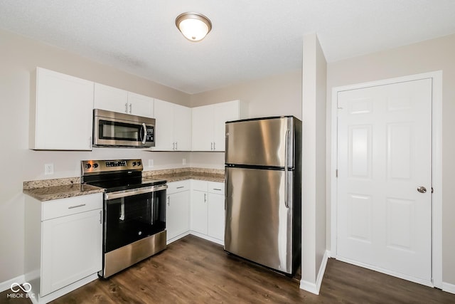 8310 Becks Mill Ln, Indianapolis, IN 46113 - kitchen with appliances with stainless steel finishes, dark wood-type flooring, white cabinetry, and light stone counters